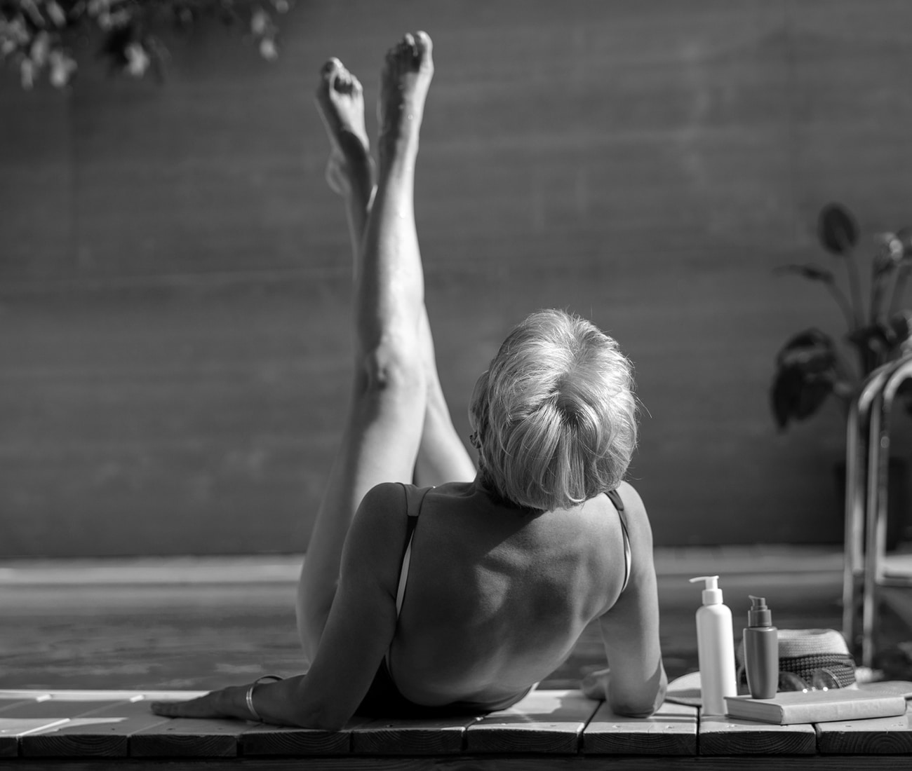 A Woman Lying Next To A Jacuzzi With Her Legs Crossed And Up In The Air, Black And White Photo